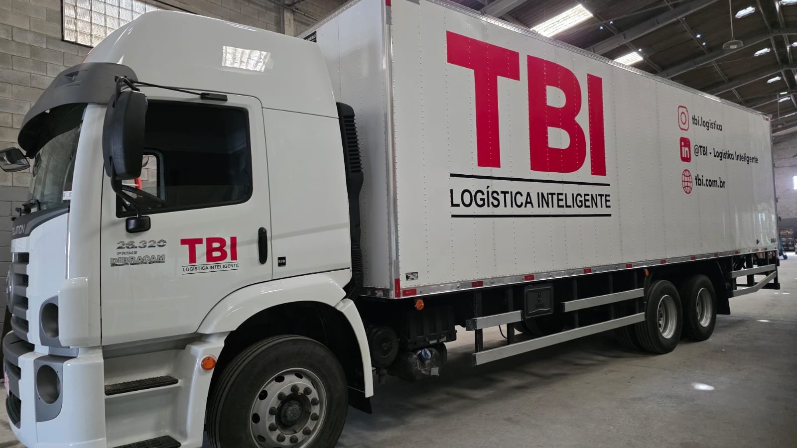 Caminhão baú da frota própria da TBI, estacionado no galpão