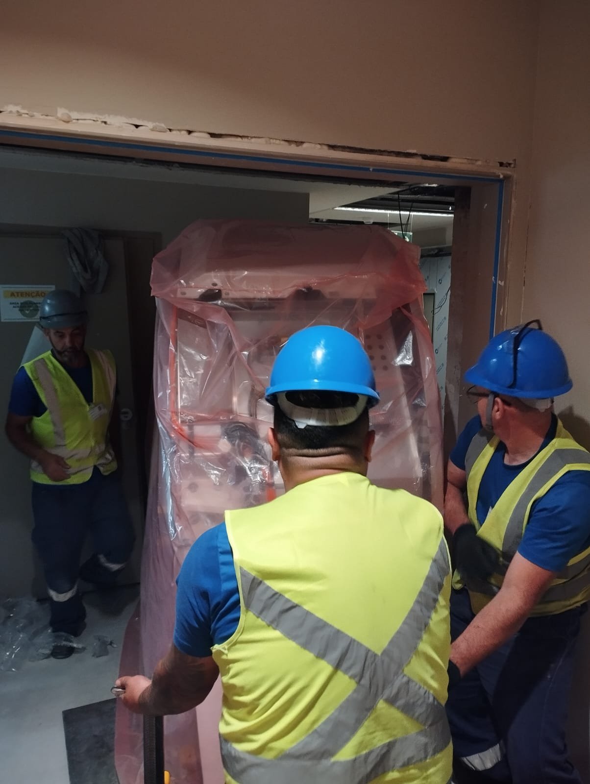 Equipamento embalado sendo conduzido por vão estreito entre salas